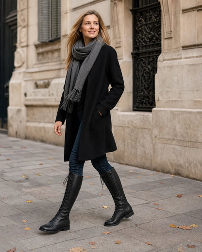 Women's black lace-up knee-high boots, autumn city walking view.
