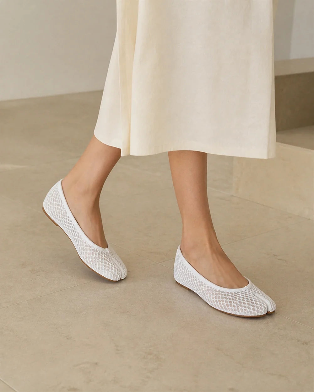 Women's white mesh tabi ballet flats, walking view.