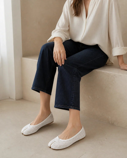 Women's white mesh tabi ballet flats, seated styling view.