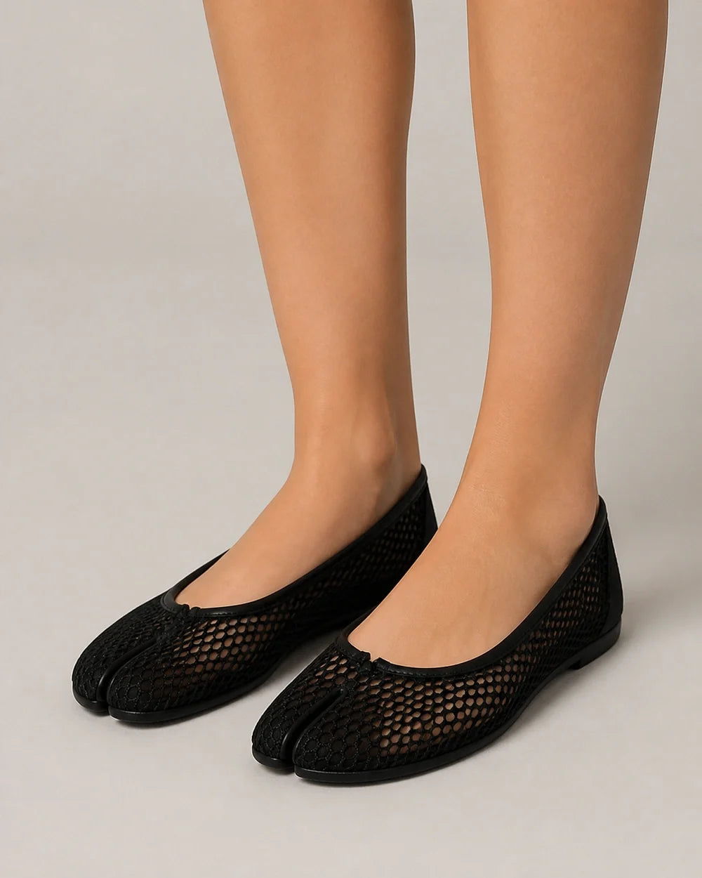 Women's black mesh tabi ballet flats, worn front three-quarter view.